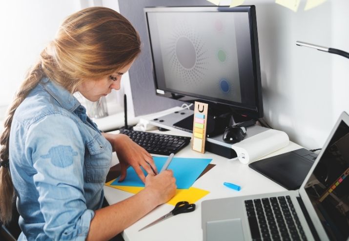 La fotografía muestra a una joven diseñadora gráfica realizando un proyecto para trabajar en Fiverr