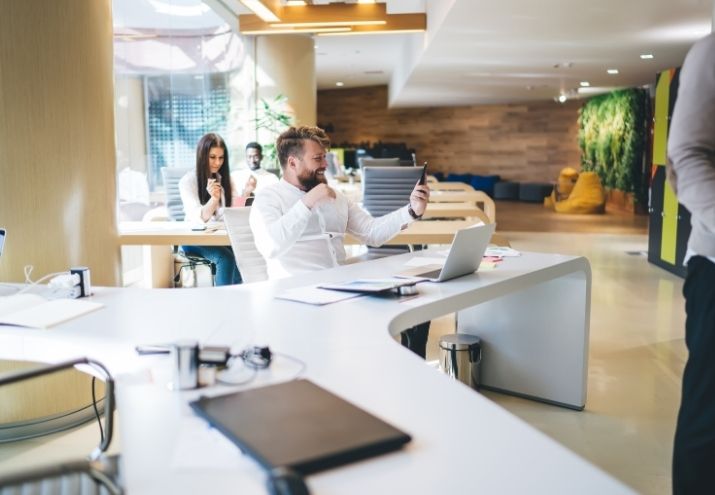 La fotografía evoca cómo sería trabajar en Google, mostrando a un trabajador que celebra sus logros en una oficina amplia y luminosa