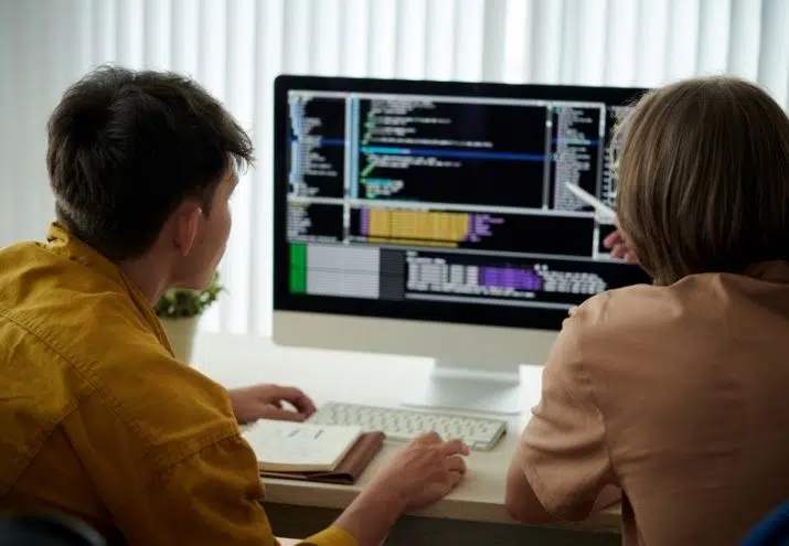 La imagen muestra a dos programadores junior programando tras conseguir empleo