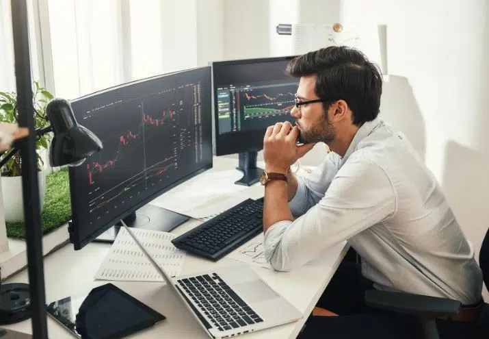La fotografía muestra a un analista de datos junior en su empleo, revisando unas gráficas en su ordenador